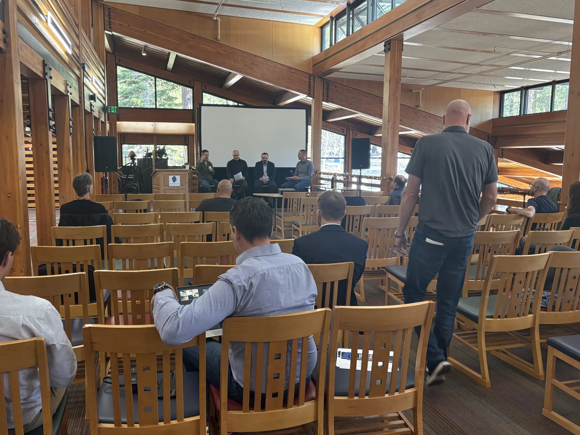 Four panelists on stage at the UNR Lake Tahoe executive roundtable, audience seated in wooden chairs in a timber-frame lodge